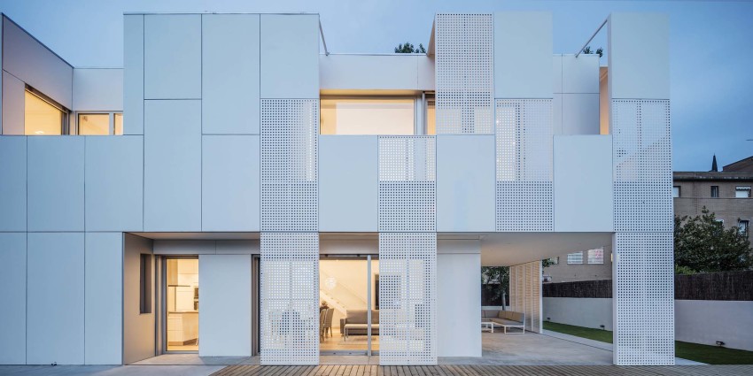 Perforated facade providing ventilation and privacy for homes.